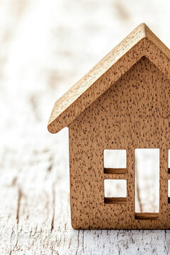 A miniature wooden house perched on a wooden table, ideal for dioramas or decorative purposes vertical frame