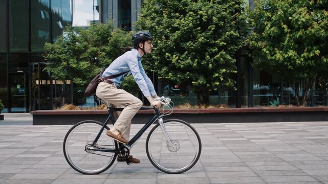 Man rides bicycle across quiet urban plaza near offices