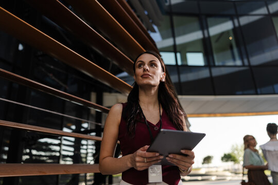 Businesswoman Using Tablet in Modern Office While Collaborating With Team Members Outdoors