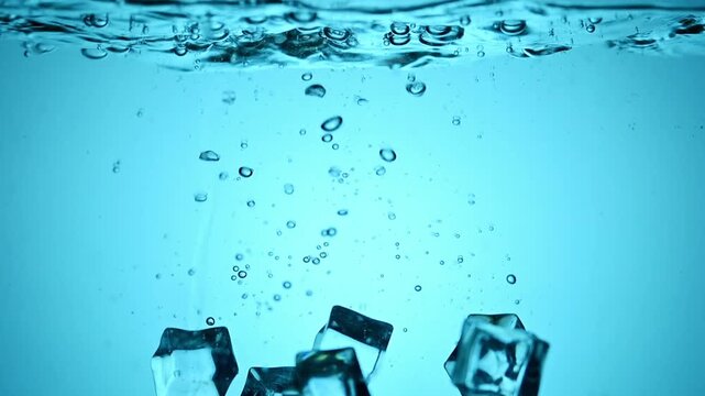 Several ice cubes falling into cool, clear blue water, creating a refreshing cascade of bubbles and ripples. The crispness of the water is evident as the ice transforms the liquid