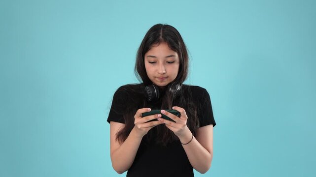 Young teenager girl playing mobile game and blowing a bubblegum