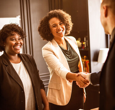 Professional women shaking hands in a warm office meeting