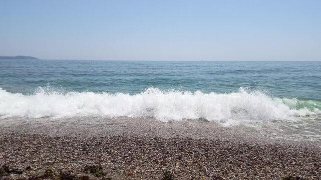 Intense close up detail of blue ocean water waves breaking in spectacular slow motion onto a dark pebble shingle beach shoreline. Charlestown Cornwall United Kingdom