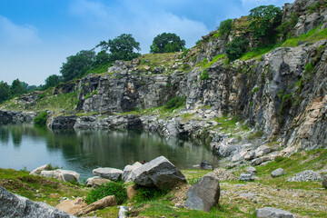 Fototapeta premium Rocks and stones of Tarpania Lake, Marble Lake, Blue Dam, Patal Dam or Durga Bera,a scenic lake in the Ajodhya Hills of Purulia, West Bengal, India. Blue water surrounded by marble-like rocky cliffs.