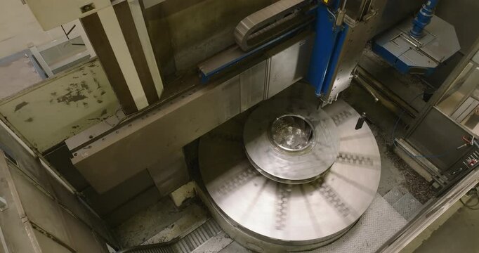 Top view of an industrial machine tool performing a precision operation on a circular metal component