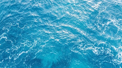 Obraz premium Gentle ocean wave texture viewed from above, abstract blue sea water background with white foam, clean tropical resort backdrop and copy space