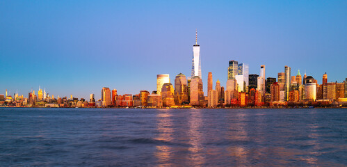 Obraz premium NTC at dusk. Sunset in NewYork. New York skyline at evening. New York downtown towers illuminated. New York Hudson waterfront scene. New York iconic city view.
