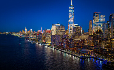 Obraz premium New York skyline with cloudy sky. New York downtown shines warm gold. New York City highlights Manhattan skyline. NYC waterfront panorama at night.