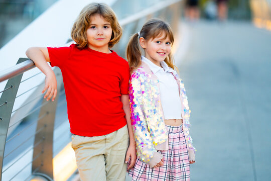 Friends kids walk hand in hand. Children friends look at each other. Young friends on city walkway. Cute friends boy and girl in outdoor portrait.