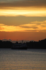 Obraz premium Ferry Ship at Twilight on Calm Tropical Sea with Island Silhouette