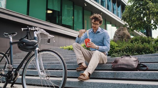 Office man eats lunch near parked bicycle after city commute