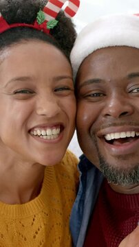 Vertical video: Pressing cheeks, couple smiling and laughing at home for holiday with Santa hat