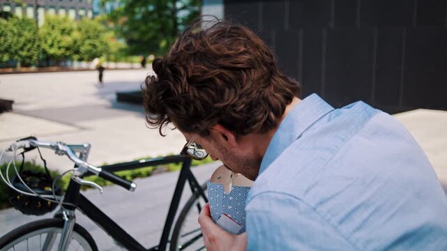 Man pauses with takeaway box near bicycle on office steps