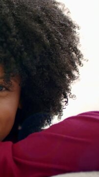 Vertical video: Filming leaning woman with big curls holding slight smile in room maroon top posing