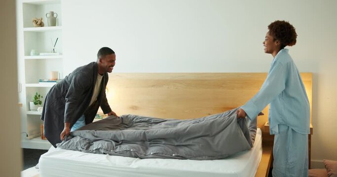 Couple, help and blanket on bed to clean house with duvet, mattress and fresh linen in morning. Happy man, black woman and tidy room in home with support, laugh and together for chores in pyjamas