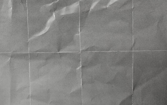 photo paper texture featuring subtle wrinkles, fold-grid creases, and soft natural light reflections. The realistic paper surface combines gentle shadows, visible paper grain, and authentic fold marks