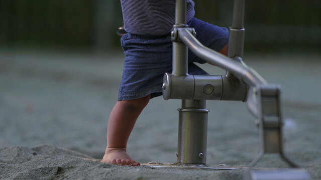 Toddler stepping into sandbox walking with unstable steps then stumbling falling and getting up again before sitting on playground digger capturing resilience and playful exploration