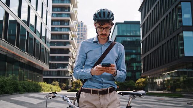 Focused man scans office courtyard with smartphone and bicycle