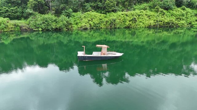 Aerial drone footage ascending above an emerald flooded quarry surrounded by dense tropical rainforest  near Crique Crabe , French Guiana.