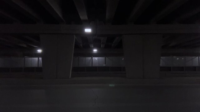 Dark empty car tunnel illuminated by rows of bright overhead lights at night