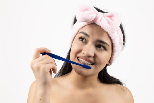 Young woman brushing her teeth with toothbrush on white background
