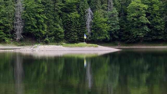 Lake Synevyr with a small island and Ukrainian flag in the Carpathian Mountains