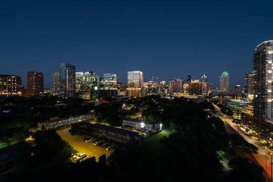 Night time view of the skyscrapers and office buildings in downtown Dallas, Texas glowing just afer sunset as seen from the roof of a building.