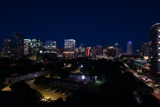 Night time view of the skyscrapers and office buildings in downtown Dallas, Texas glowing just afer sunset as seen from the roof of a building.