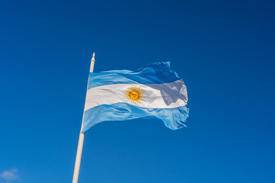 National flag of Argentina waving on a flagpole against a clear blue sky