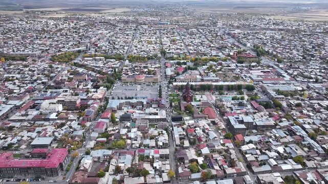 Aerial drone shot of the beautiful city of Gyumri in Armenia, showcasing its historic architecture, busy city squares, streets, and the famous landmark Holy Saviour's Church during autumn.


