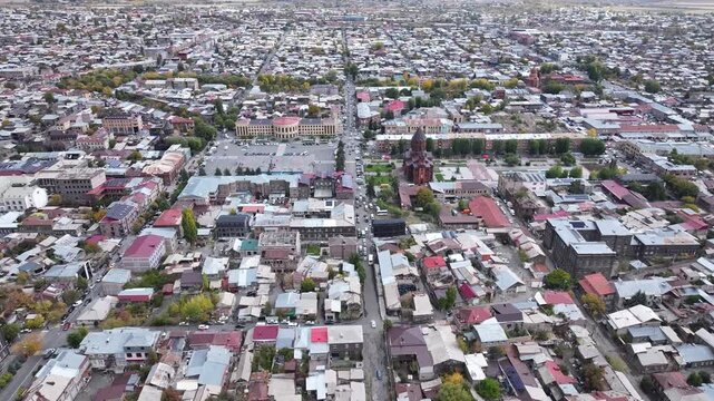 Aerial drone shot of the beautiful city of Gyumri in Armenia, showcasing its historic architecture, busy city squares, streets, and the famous landmark Holy Saviour's Church during autumn.

