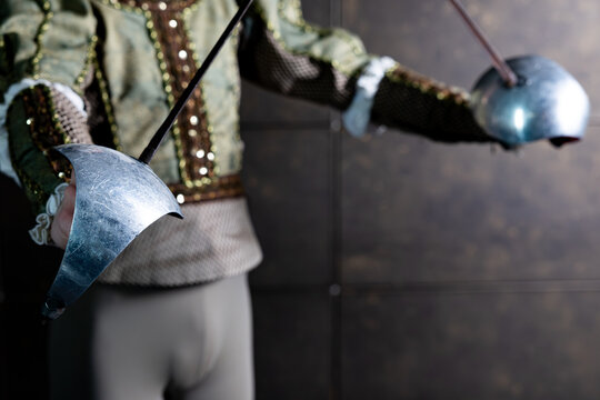 Fencer in vintage historical costume holding crossed rapiers swords from Don Quixote performance