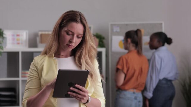 Professional businesswoman using tablet smiles at the camera