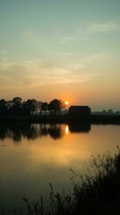 Naklejka premium Rural barn silhouetted against a golden sunrise over a calm lake with reflections