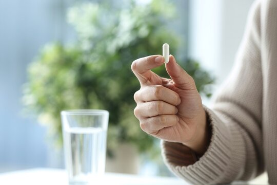 White capsule held by a hand close up pharmaceutical photo
