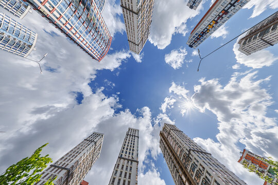view from below into blue sky with clouds of large modern skyscraper residential complex