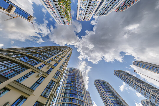 view from below into blue sky with clouds of large modern skyscraper residential complex