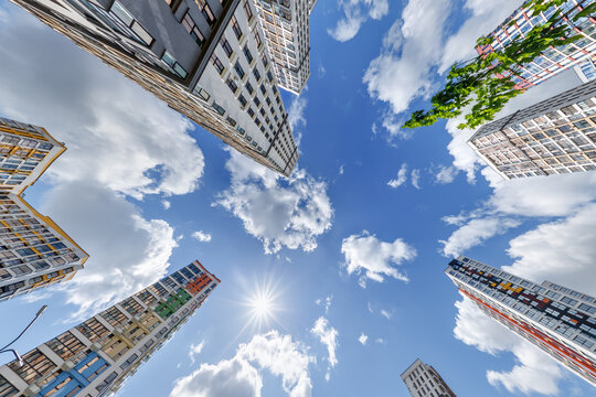 view from below into blue sky with clouds of large modern skyscraper residential complex