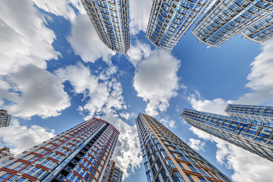 view from below into blue sky with clouds of large modern skyscraper residential complex