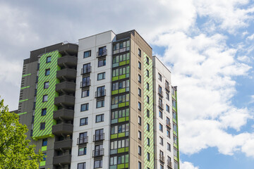 Fototapeta premium Modern apartment building facades with green and dark grey color blocks under sunny blue sky. Urban