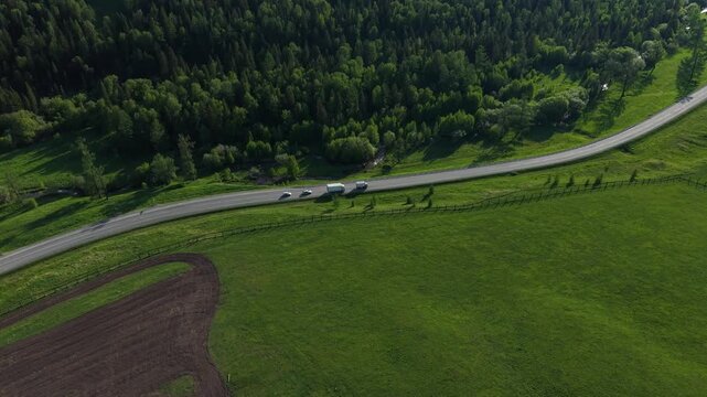 A high-angle drone shot of cars performing a risky double overtaking maneuver on a narrow winding mountain highway near Seminsky Pass.