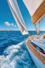 Fototapeta premium Sailboat cutting through blue ocean waves with full sails on a sunny summer day