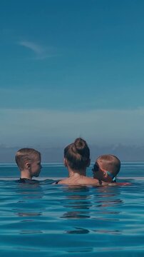 Woman With Two Boys In Pool, Floating Toward Horizon Under Blue Sky, Calm Turquoise Water, Gentle Splashes, Mother Guiding Children, Relaxed Vacation Mood, Carefree Summer Bonding,Bali island