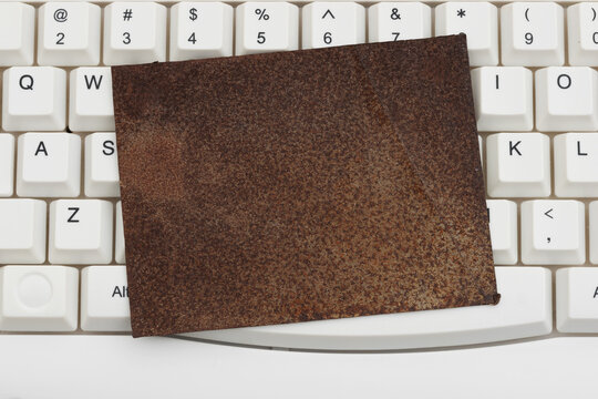 Blank rusty sign on a white computer keyboard for outdated systems