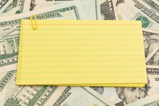 Blank lined index cards on twenty dollar bills for financial planning and budgeting