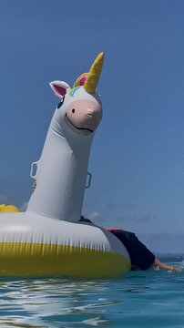 Bright unicorn float. Colorful inflatable unicorn head. Sunlit glossy unicorn with vibrant mane. Cheerful inflatable unicorn with suncatching surface and colorful hair, vertical video