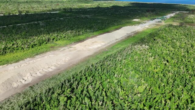Aerial view of North Field Base runway surrounded by dense tropical vegetation and coastal landscape in Northern Tinian, Tinian, Northern Mariana Islands.