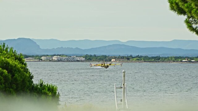 Two French Canadair firefighting planes landing on a lake and scooping water, amphibious aircraft water bombers refilling.
