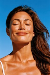 Obraz premium Smiling woman with eyes closed enjoying sun and warm breeze, healthy glowing skin and relaxation