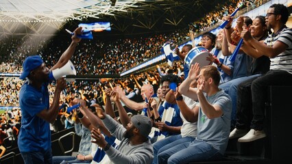 Energetic football fan with megaphone leading cheering supporters in stadium stands during intense soccer match, Supporters in the fan zone cheering and creating powerful stadium noise. © DC Studio